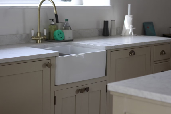 modern kitchen with a farmhouse sink stylish cabinetry and brass faucet featuring dish soap and kitchen accessories in a well-lit space ideal for home cooking